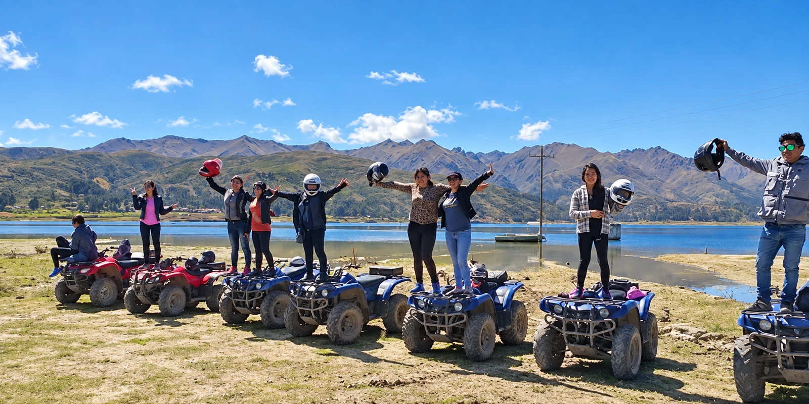 Grupo de viajeros sobre cuatrimotos junto a una laguna y las montañas de Cusco