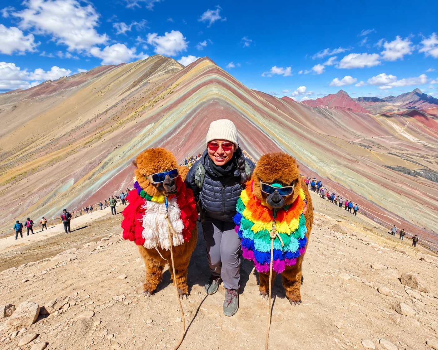 Una viajera con dos alpacas frente a la montaña Vinicunca